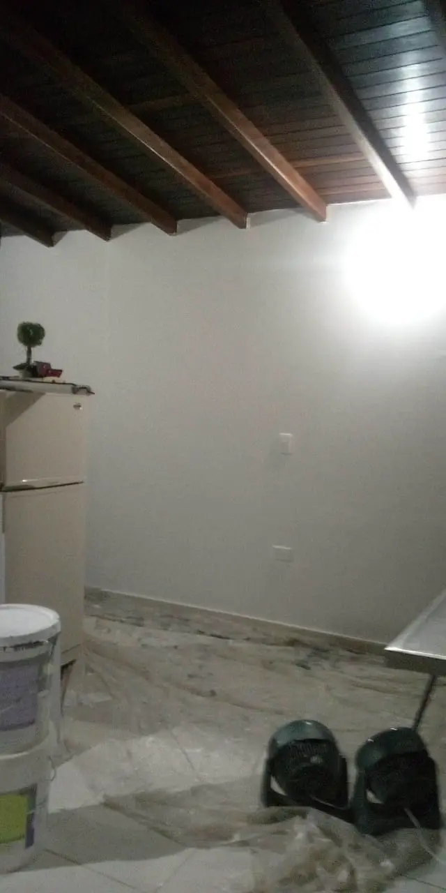 Room being painted with a wooden beam ceiling and a covered floor