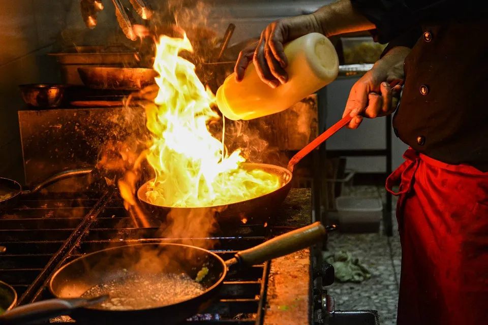 Chef cooking with a flame in the hostel kitchen